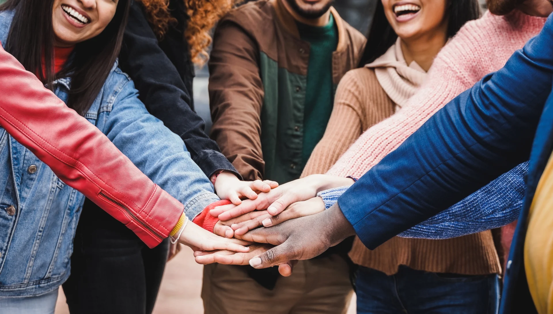 A diverse group stacking hands in unity and teamwork.