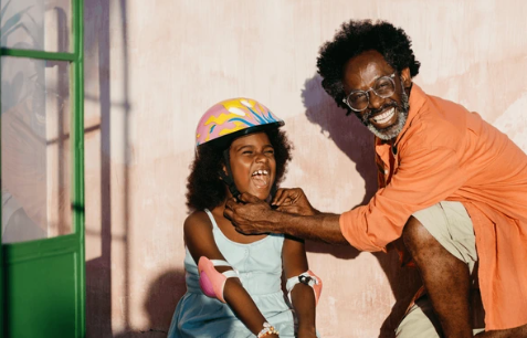 Father playfully pretending to choke his laughing daughter.