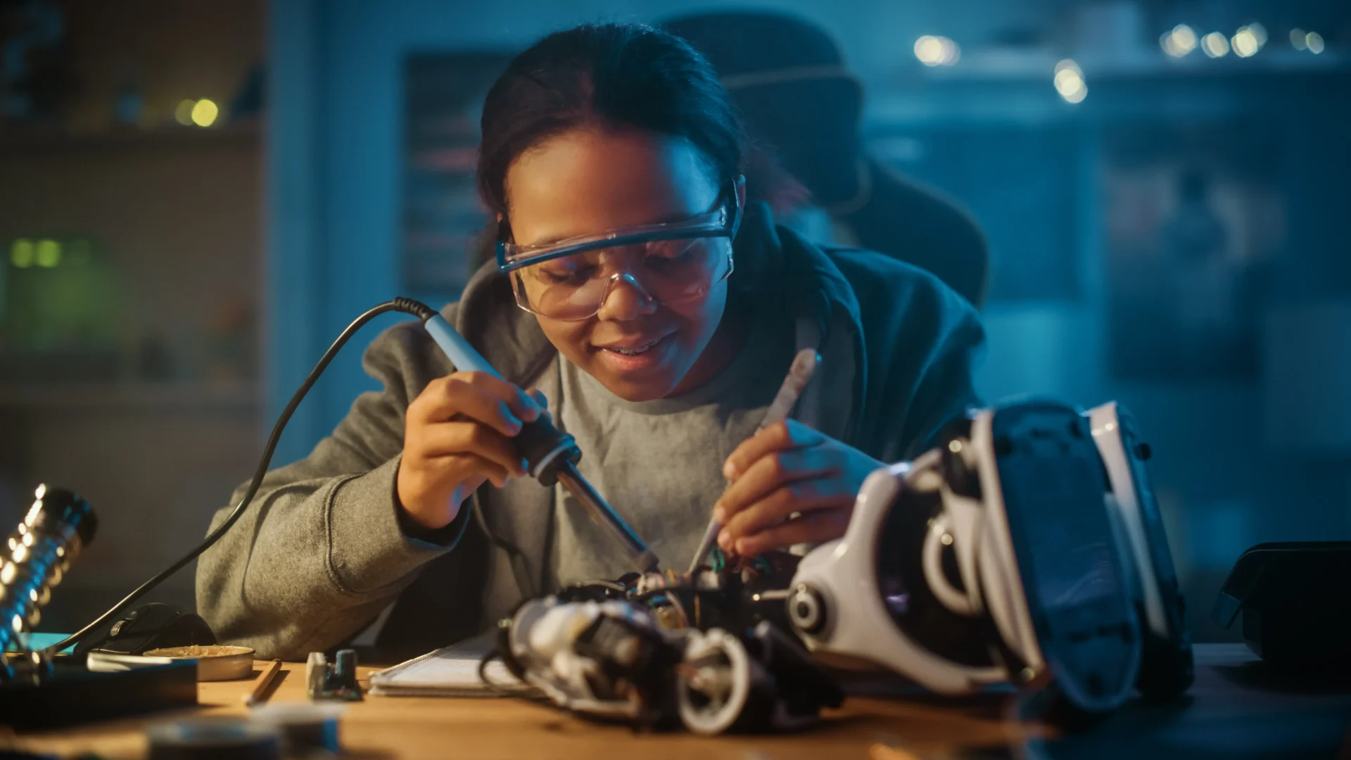 Engineer soldering components on a robotic device in a lab.